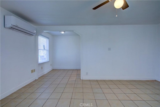 spare room with a wall unit AC, baseboards, a ceiling fan, and light tile patterned flooring