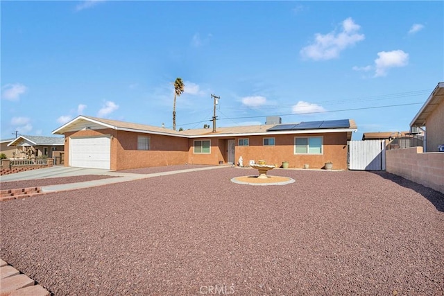 ranch-style house featuring a garage, solar panels, fence, concrete driveway, and a gate