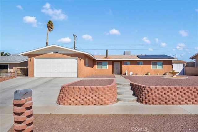 single story home with a garage, solar panels, fence, concrete driveway, and stucco siding