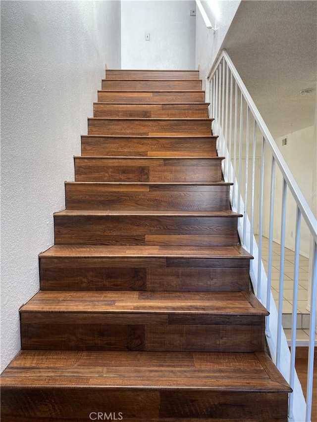 stairway featuring a textured wall