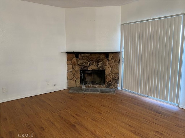 unfurnished living room featuring a fireplace, wood finished floors, and baseboards