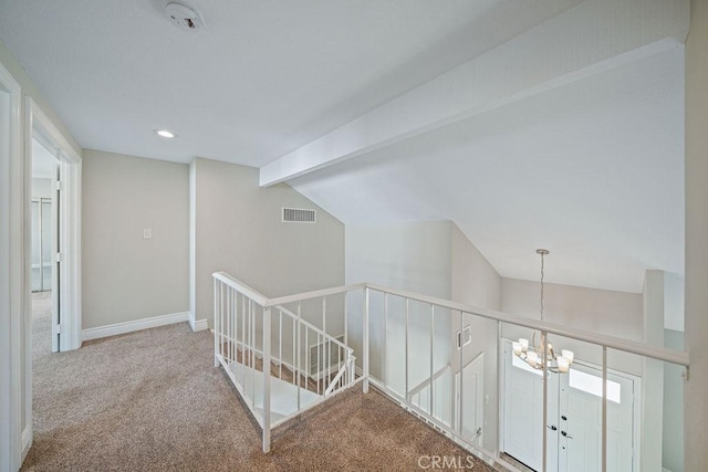 hall with vaulted ceiling with beams, visible vents, an inviting chandelier, carpet flooring, and an upstairs landing