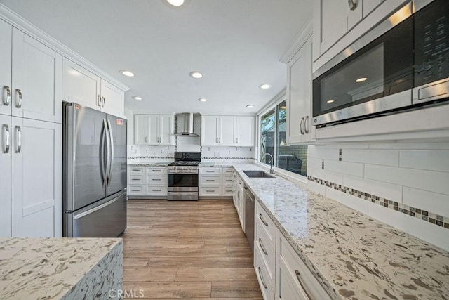 kitchen featuring wall chimney exhaust hood, appliances with stainless steel finishes, light wood-type flooring, and white cabinets