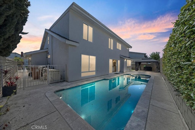 pool at dusk with a fenced in pool, fence, a gazebo, and a patio