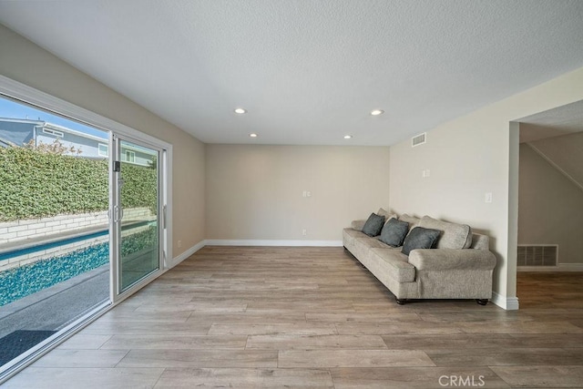 interior space with light wood finished floors, baseboards, visible vents, and a textured ceiling