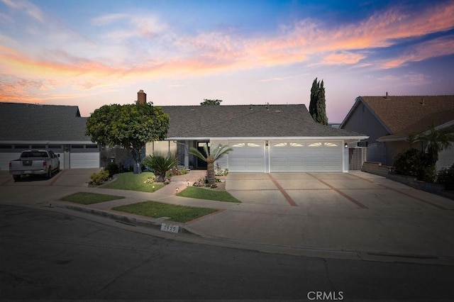 view of front of house featuring an attached garage, a chimney, and concrete driveway