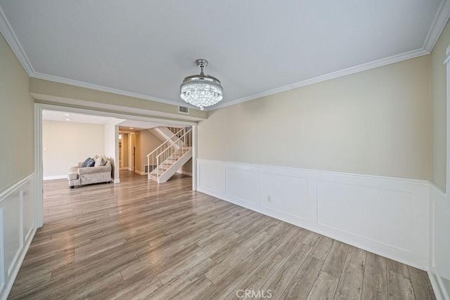 unfurnished dining area featuring crown molding, visible vents, wood finished floors, a chandelier, and stairs