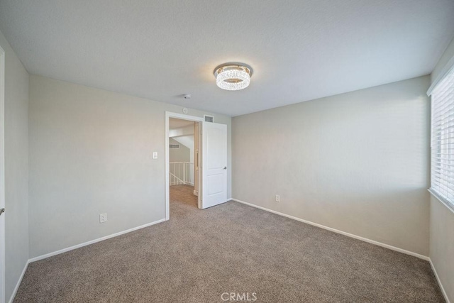 unfurnished room featuring carpet floors, visible vents, and baseboards