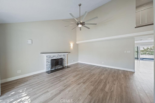 unfurnished living room with baseboards, a fireplace with raised hearth, and wood finished floors