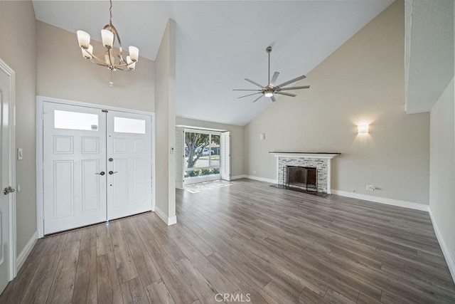 foyer with high vaulted ceiling, ceiling fan with notable chandelier, a fireplace, wood finished floors, and baseboards