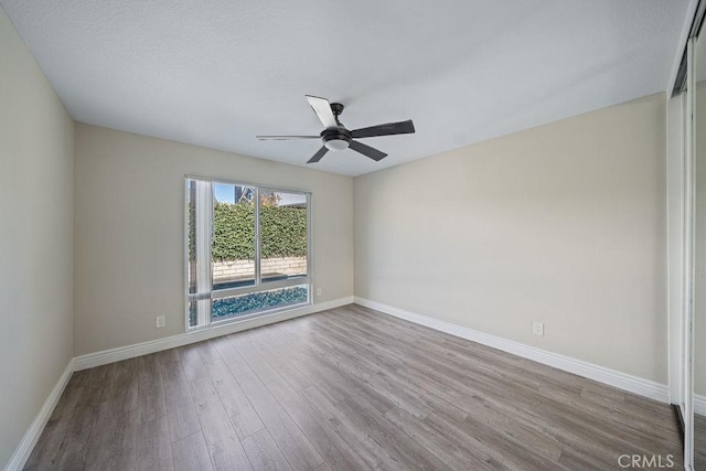 unfurnished room featuring ceiling fan, wood finished floors, and baseboards