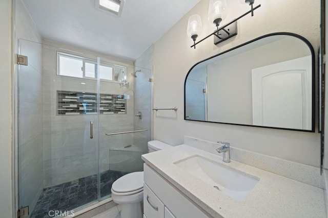 bathroom with a stall shower, visible vents, vanity, and toilet