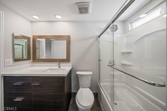 bathroom with visible vents, shower / bath combination with glass door, vanity, and toilet