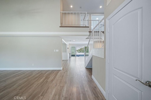 hall with stairway, a high ceiling, baseboards, and wood finished floors