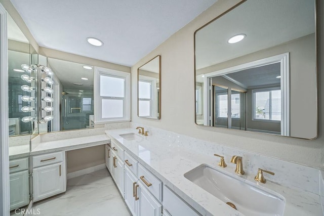 bathroom with marble finish floor, double vanity, a stall shower, and a sink