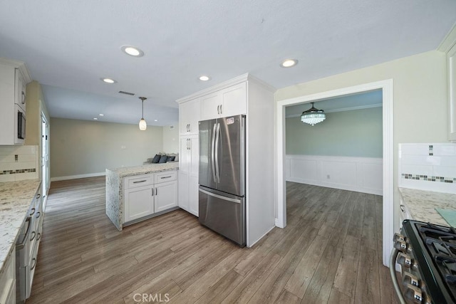 kitchen with visible vents, backsplash, appliances with stainless steel finishes, wood finished floors, and a peninsula