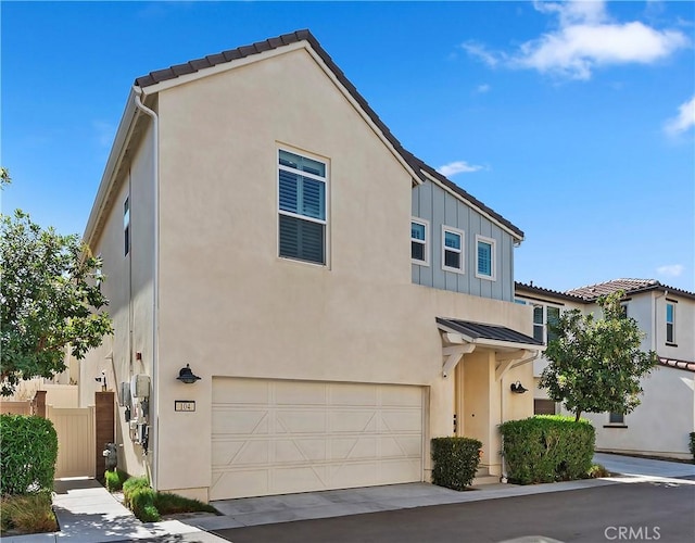 view of front of house with an attached garage, fence, metal roof, and stucco siding