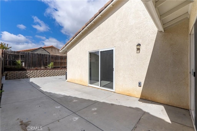 exterior space featuring a patio area, fence, and stucco siding