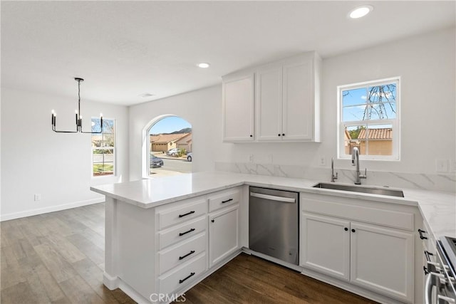 kitchen with a peninsula, dark wood-style flooring, a sink, white cabinetry, and appliances with stainless steel finishes