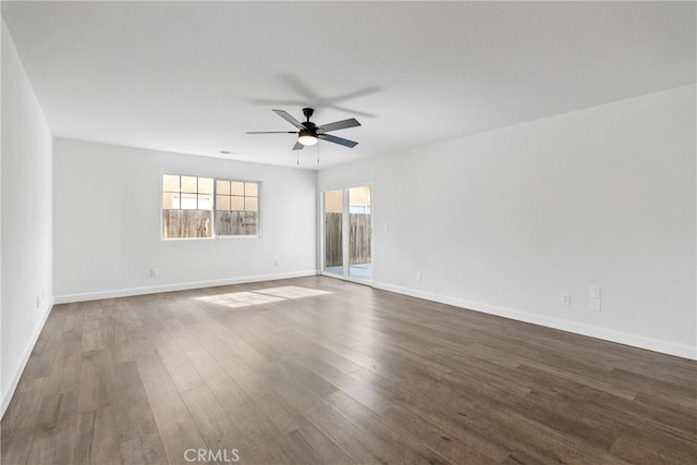 spare room featuring baseboards, a ceiling fan, and dark wood-type flooring