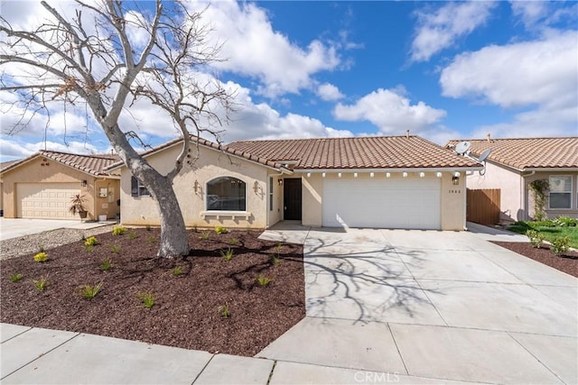 mediterranean / spanish-style home with concrete driveway, an attached garage, a tile roof, and stucco siding