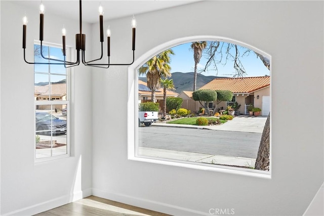interior space with a notable chandelier, baseboards, a mountain view, and wood finished floors
