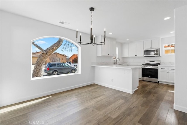 kitchen with dark wood-type flooring, a sink, white cabinetry, light countertops, and appliances with stainless steel finishes