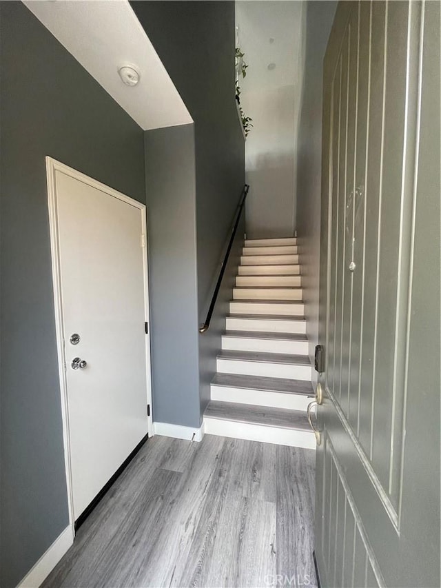 staircase featuring wood finished floors and baseboards