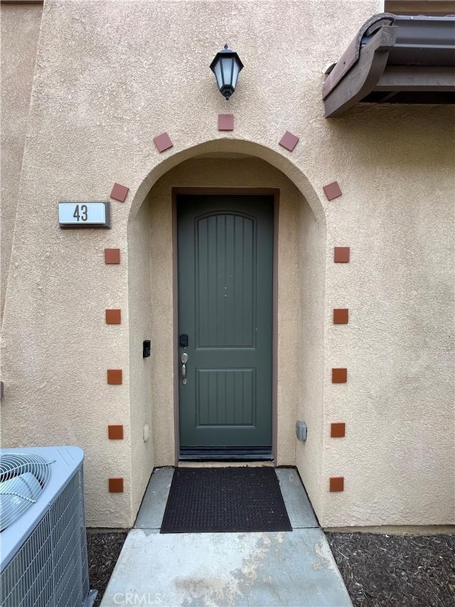 entrance to property featuring central AC unit and stucco siding