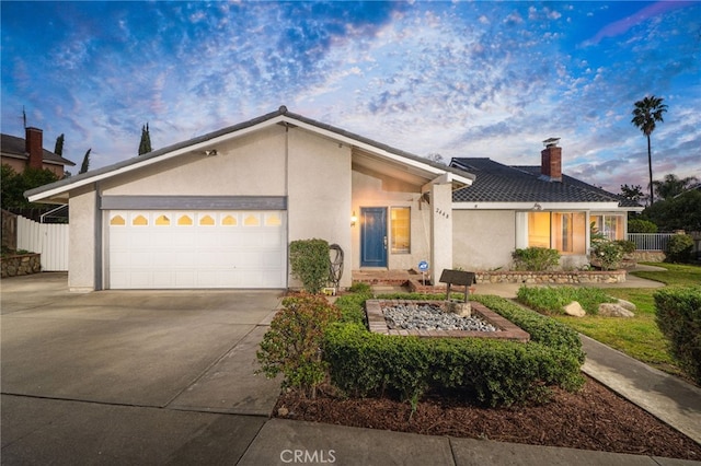 mid-century inspired home featuring driveway, fence, an attached garage, and stucco siding