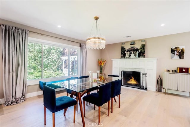 dining area featuring baseboards, an inviting chandelier, light wood-style flooring, recessed lighting, and a lit fireplace