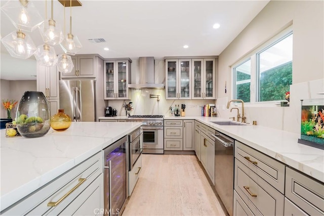 kitchen featuring visible vents, beverage cooler, stainless steel appliances, wall chimney exhaust hood, and a sink