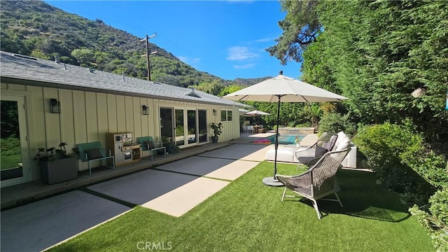 view of pool with a patio, a lawn, and a mountain view