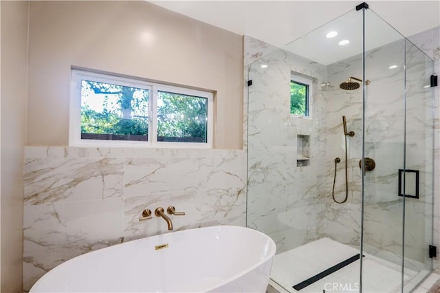 bathroom with a marble finish shower, recessed lighting, tile walls, and a freestanding tub