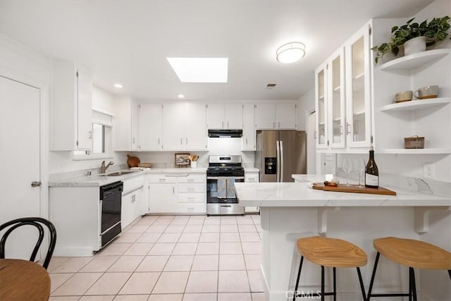 kitchen featuring a skylight, light tile patterned floors, appliances with stainless steel finishes, a peninsula, and open shelves