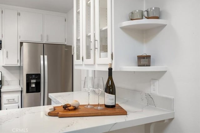 kitchen featuring open shelves, light stone countertops, white cabinets, and stainless steel fridge with ice dispenser