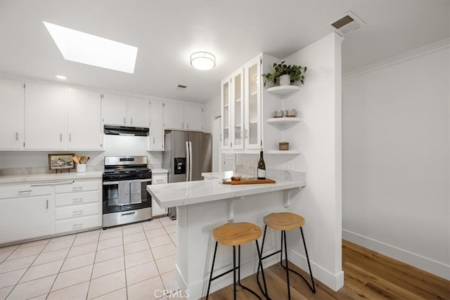 kitchen with a skylight, visible vents, white cabinets, stainless steel appliances, and under cabinet range hood