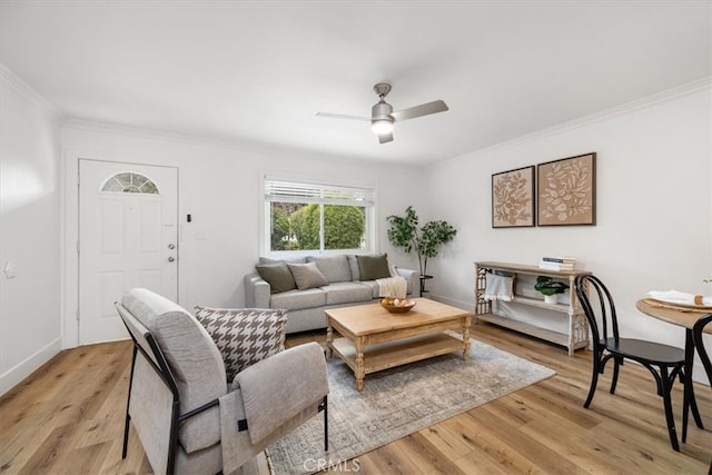 living room featuring light wood-style floors, baseboards, a ceiling fan, and crown molding