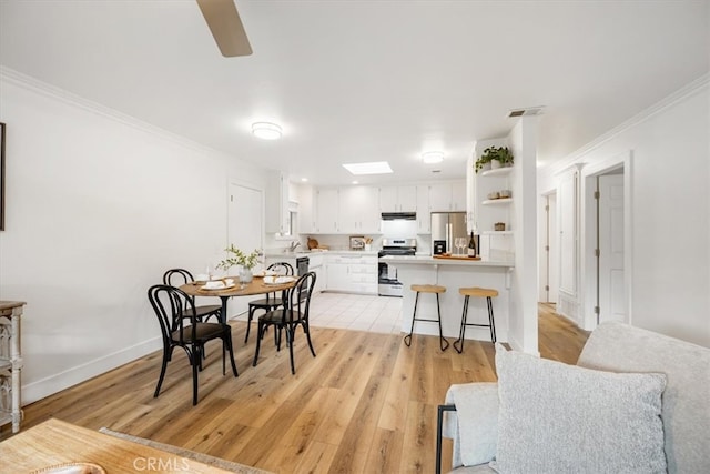 dining area with crown molding, visible vents, light wood-style flooring, ceiling fan, and baseboards