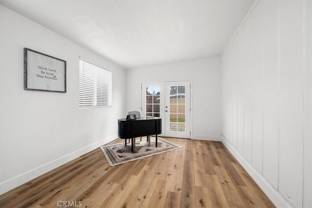 sitting room featuring light wood-style floors, french doors, and baseboards