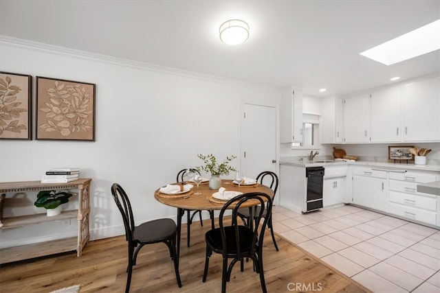 dining space featuring a skylight, light wood finished floors, baseboards, crown molding, and recessed lighting