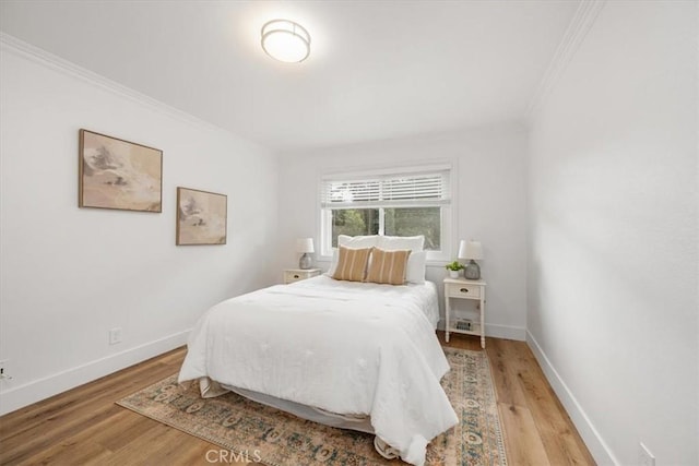 bedroom featuring ornamental molding, light wood-type flooring, and baseboards