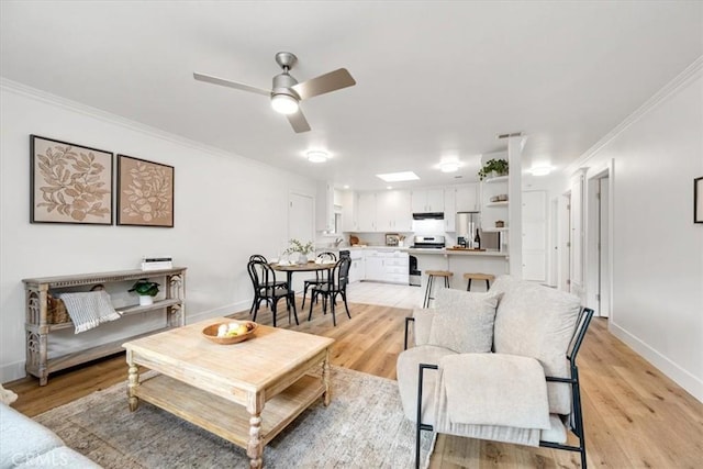 living area featuring baseboards, light wood-style flooring, and crown molding