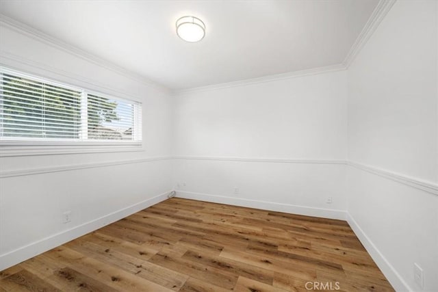 spare room with baseboards, ornamental molding, and wood finished floors