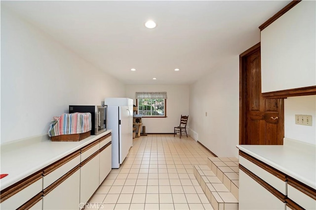 kitchen with light tile patterned floors, white cabinetry, light countertops, and freestanding refrigerator