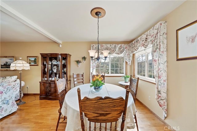 dining space featuring a chandelier, beamed ceiling, light wood-type flooring, and baseboards