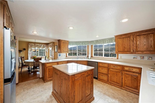 kitchen featuring a peninsula, brown cabinetry, light countertops, and stainless steel dishwasher