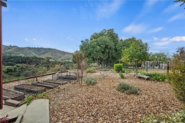 view of yard with a vegetable garden, a mountain view, and fence