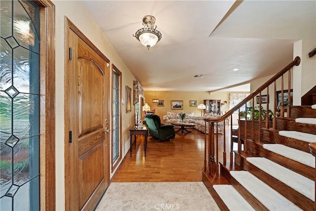 entryway with stairs, light wood-style flooring, and visible vents