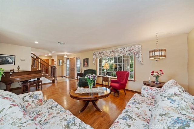 living room with baseboards, visible vents, stairway, and wood finished floors